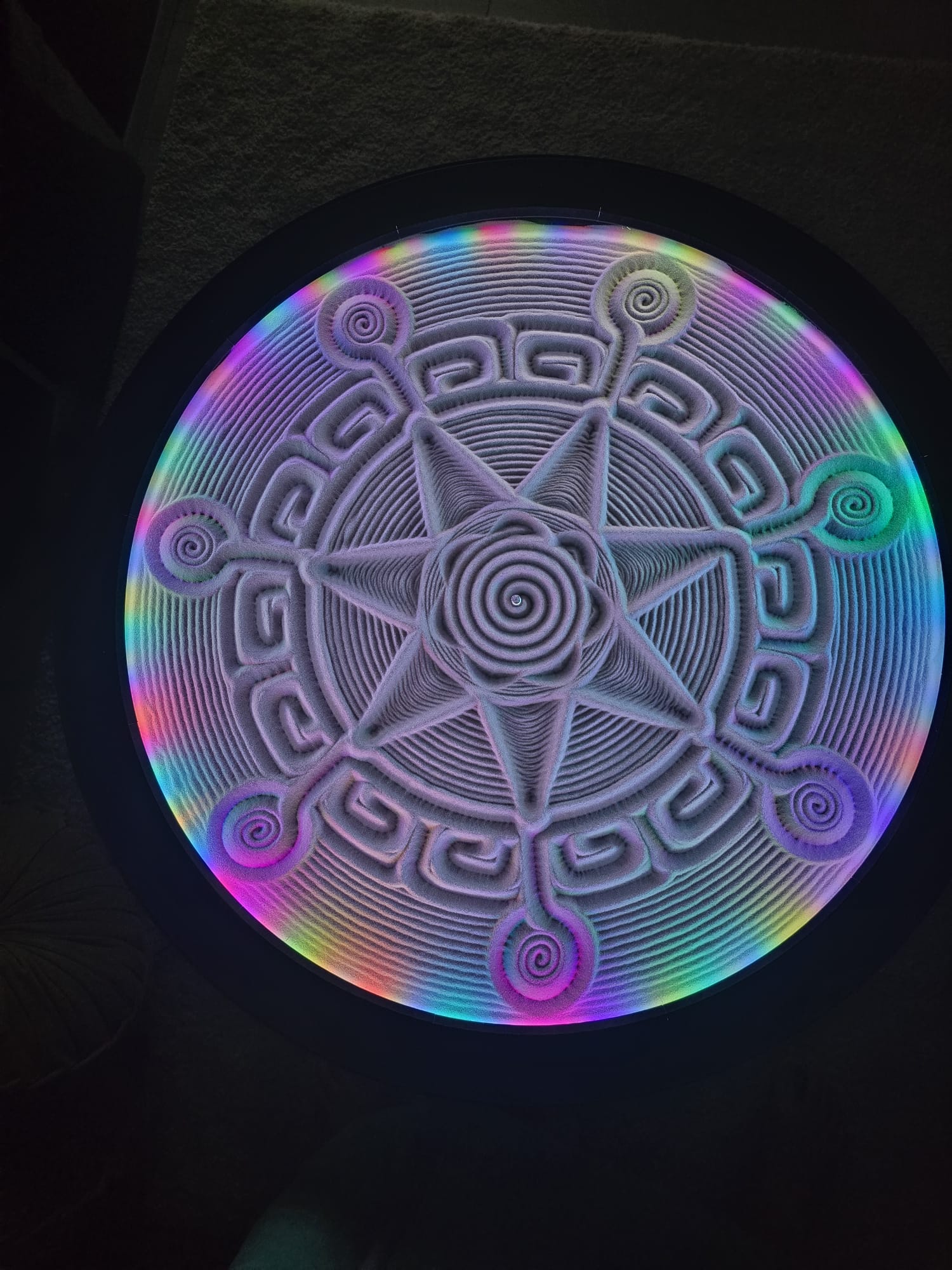 Model geometric în nisip înconjurat de lumină multicoloră
